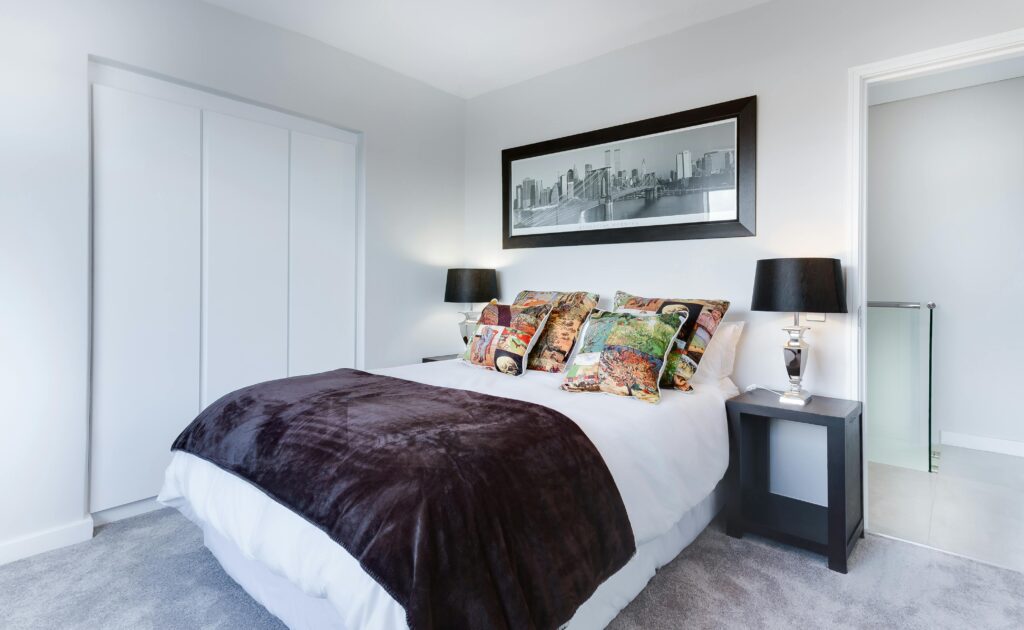 Stylish and contemporary bedroom featuring a cityscape artwork, colorful pillows, and modern decor.