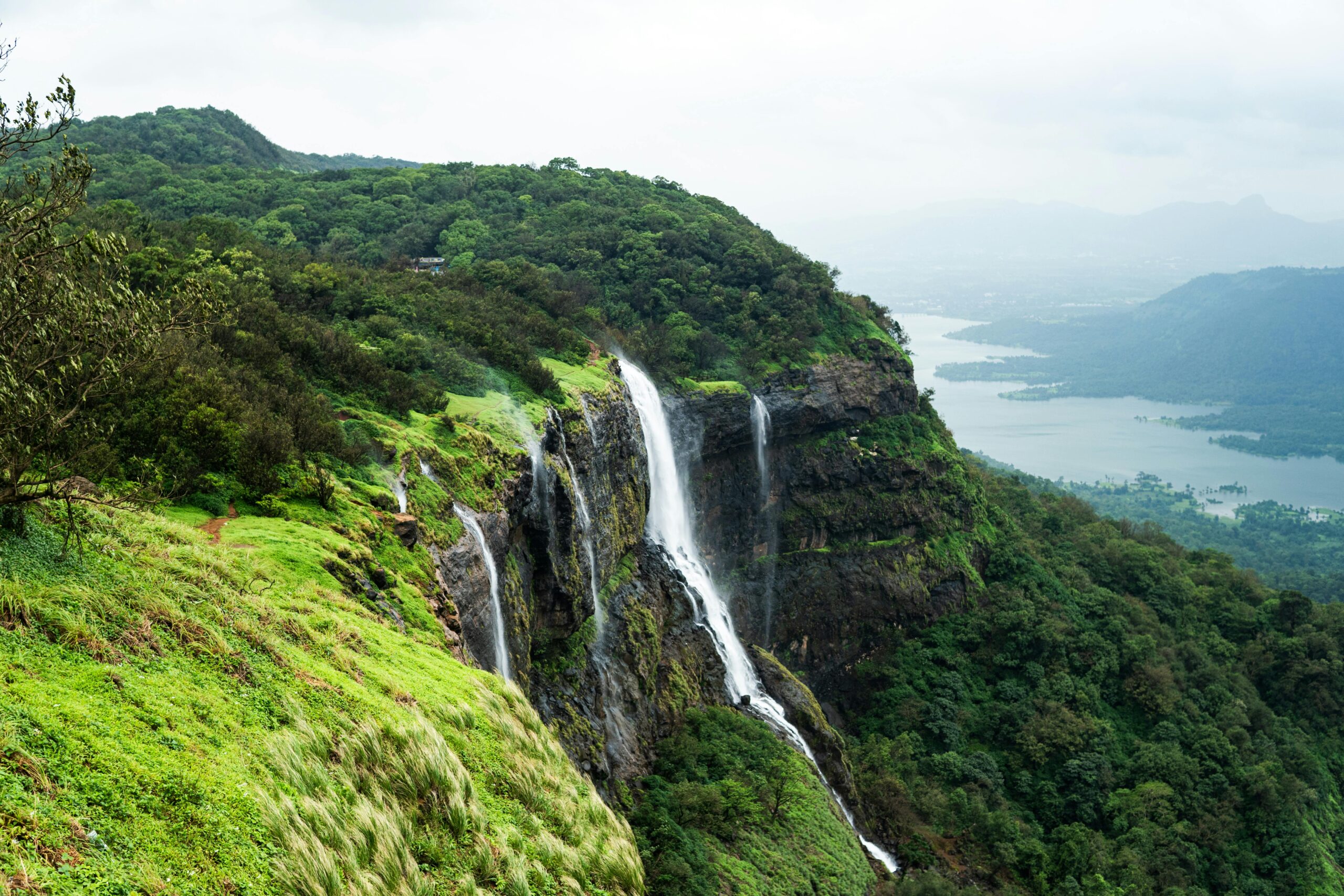 Breathtaking view of a waterfall in Matheran, India surrounded by lush greenery and serene mountains.